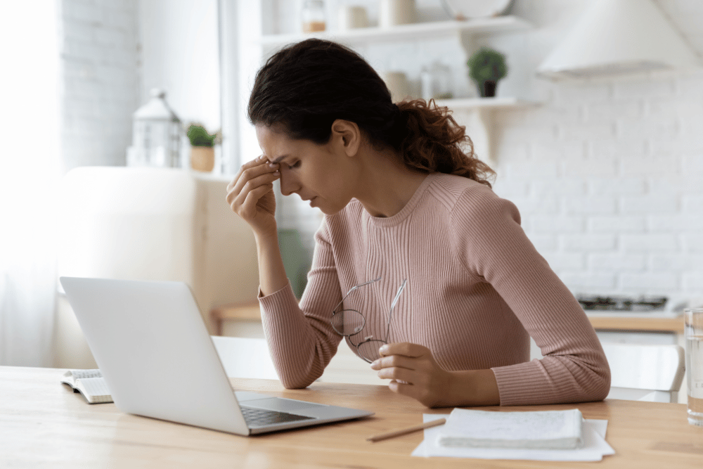 a woman removing her glasses and resting her head on her hand