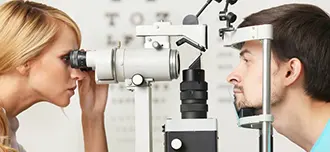 Woman checking a male patient's eyes during his eye exam