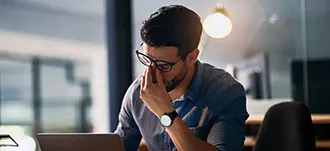 Professional male working at a computer rubbing his eyes in irritation