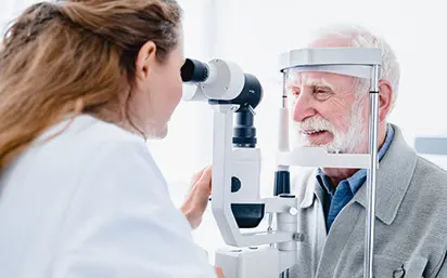 Older man getting an eye exam at the slit lamp machine
