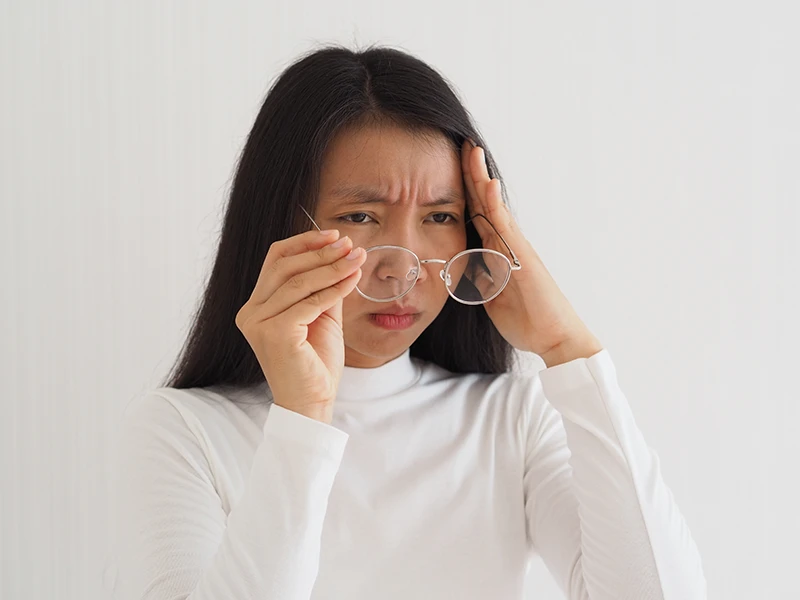 a woman taking off her glasses and looking concerned