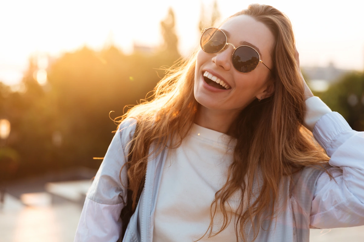 Smiling person wearing sunglasses outside